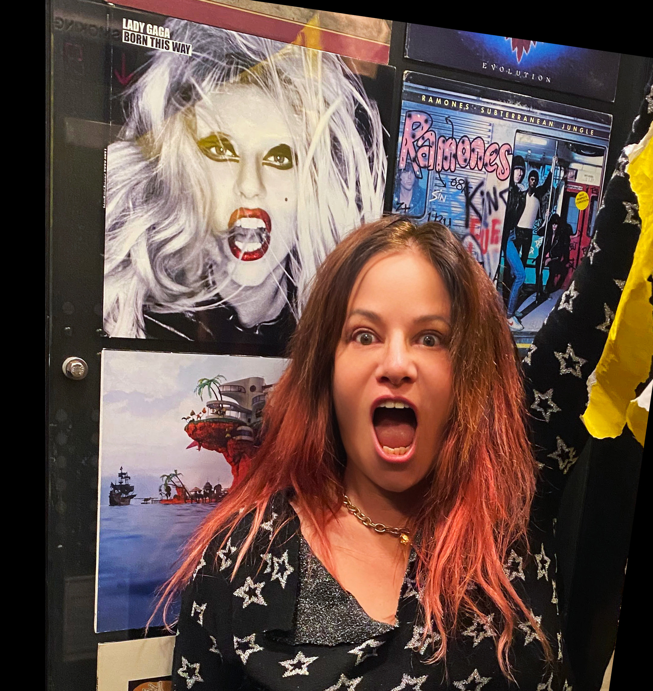 Jennifer Finch taking a selfie with the album cover for Lady Gaga's "Born This Way" in the background.