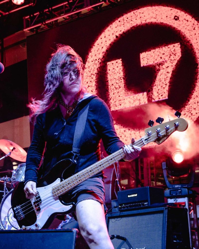 Jennifer Finch with a bass guitar performing live on stage with L7
