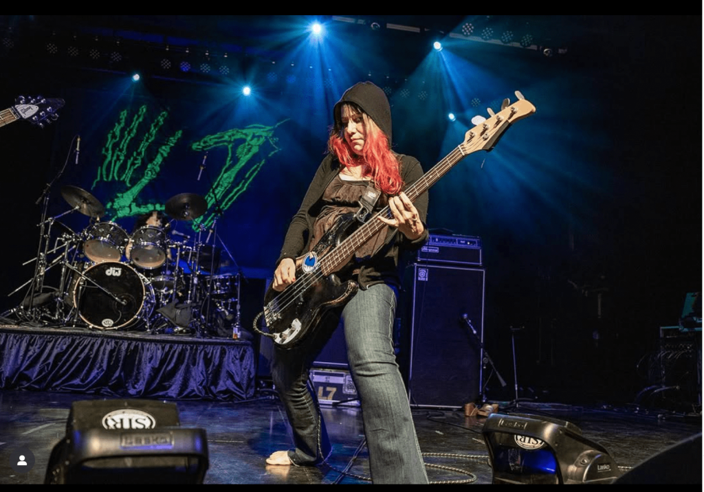 Jennifer Finch playing bass in hoodie on stage